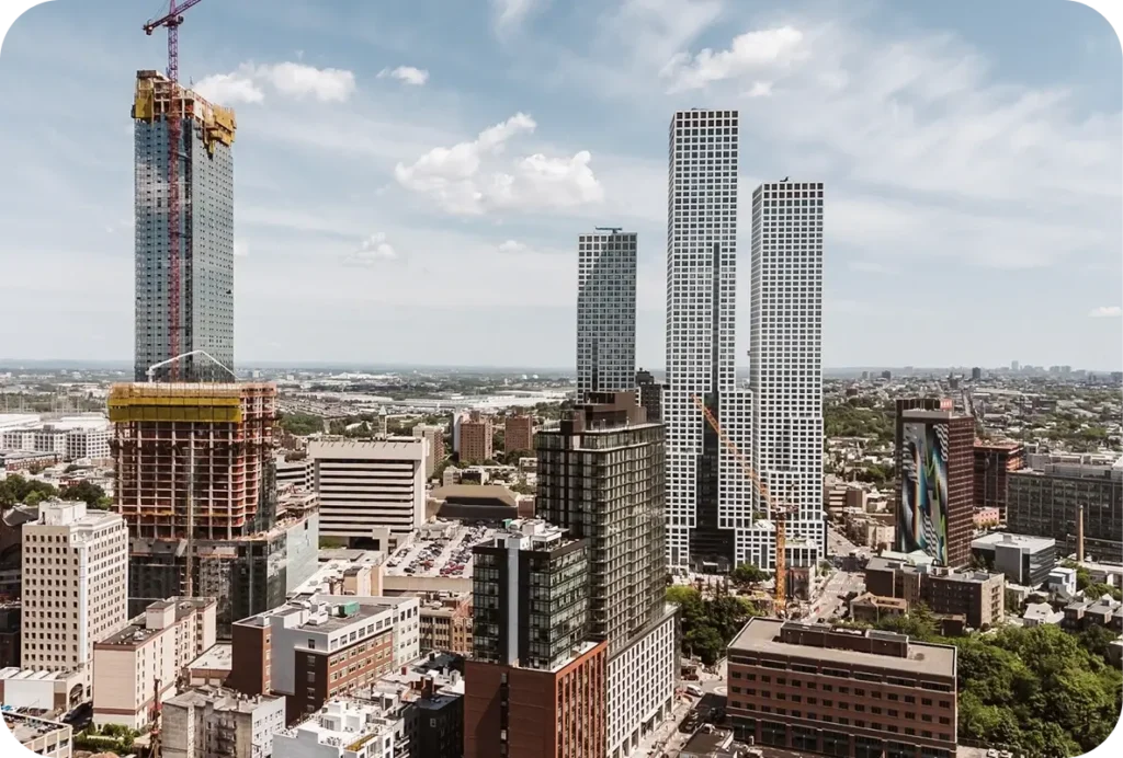 Aerial view of tall modern skyscrapers under construction in a dense urban neighborhood