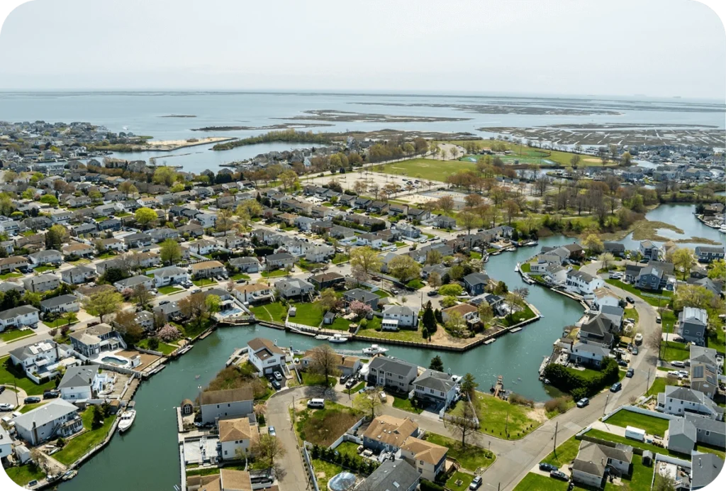Aerial view of a residential waterfront neighborhood in Long Island with inlets, boats, and nearby wetlands