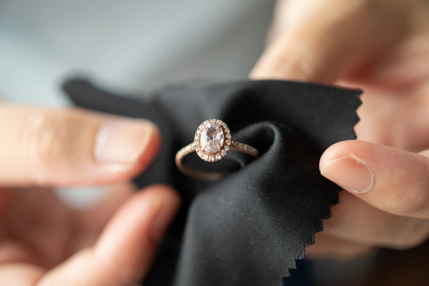 Person polishing a diamond engagement ring with a soft cloth before selling to Qollateral.
