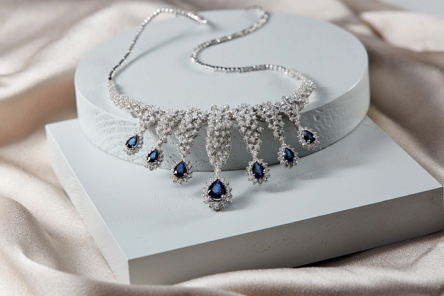 Elegant sapphire and diamond heirloom necklace with pear-shaped sapphires set in white gold and surrounded by sparkling diamonds.