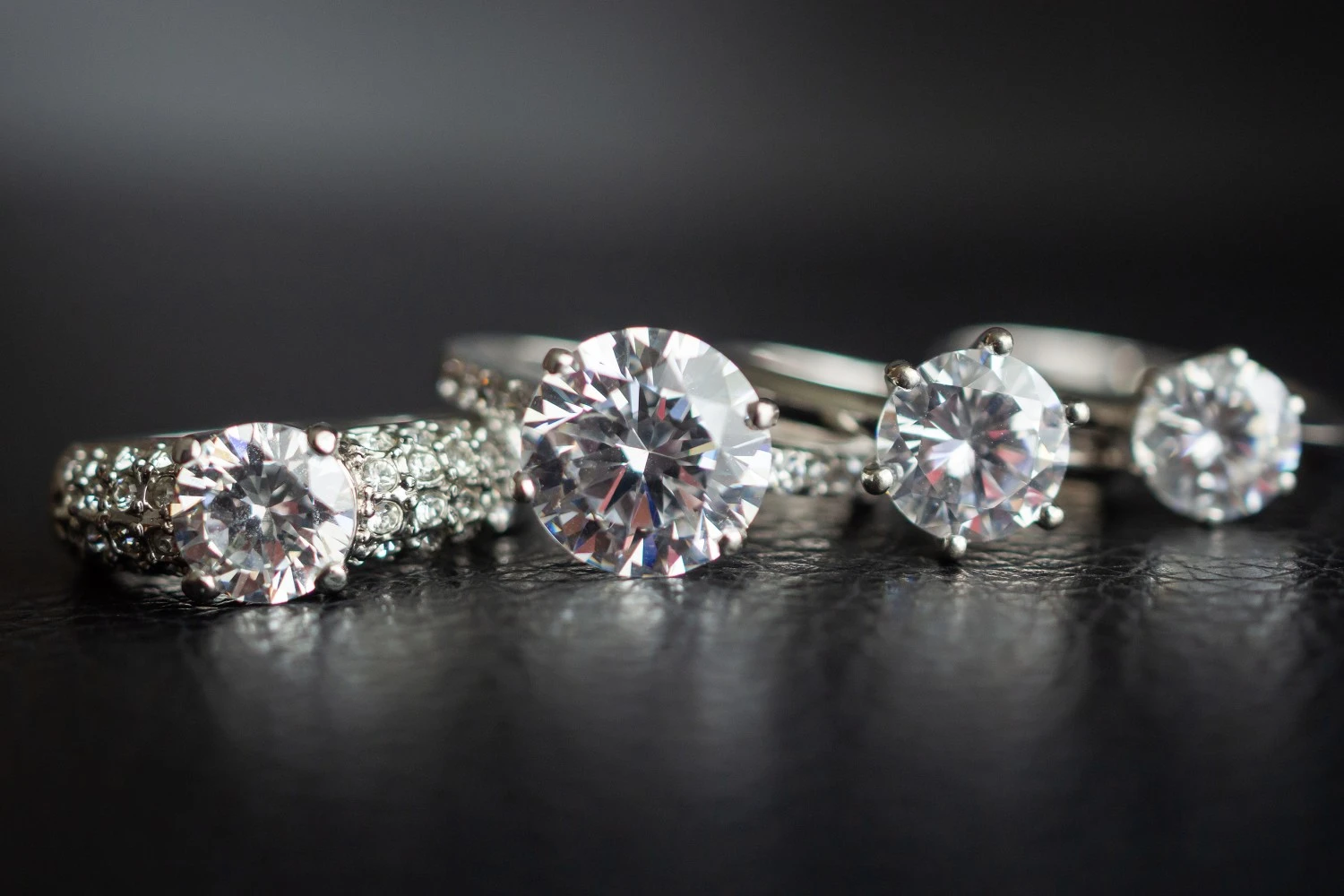 Close-up of diamond engagement rings and fine jewelry on a dark surface, representing luxury diamond collateral loans at Qollateral.