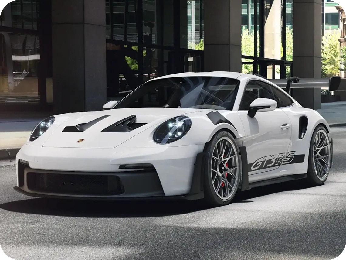 White Porsche 911 GT3 RS with rear wing parked outside a modern building