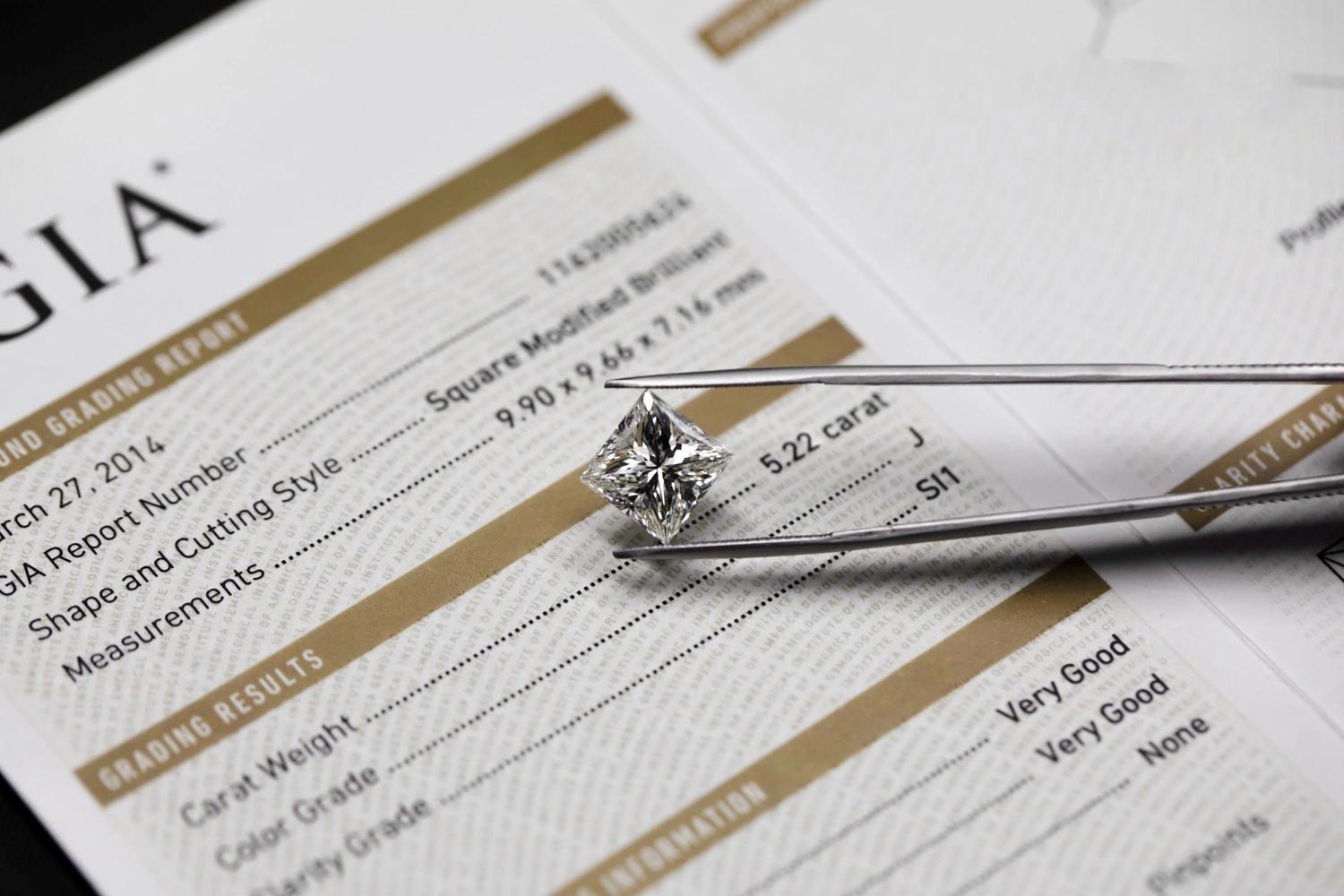Princess cut diamond held with tweezers over GIA diamond grading report
