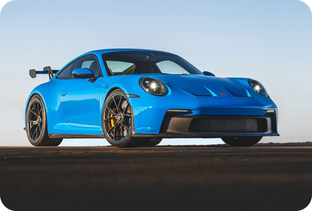 Blue Porsche 911 GT3 992 generation with swan-neck rear wing shown at dusk
