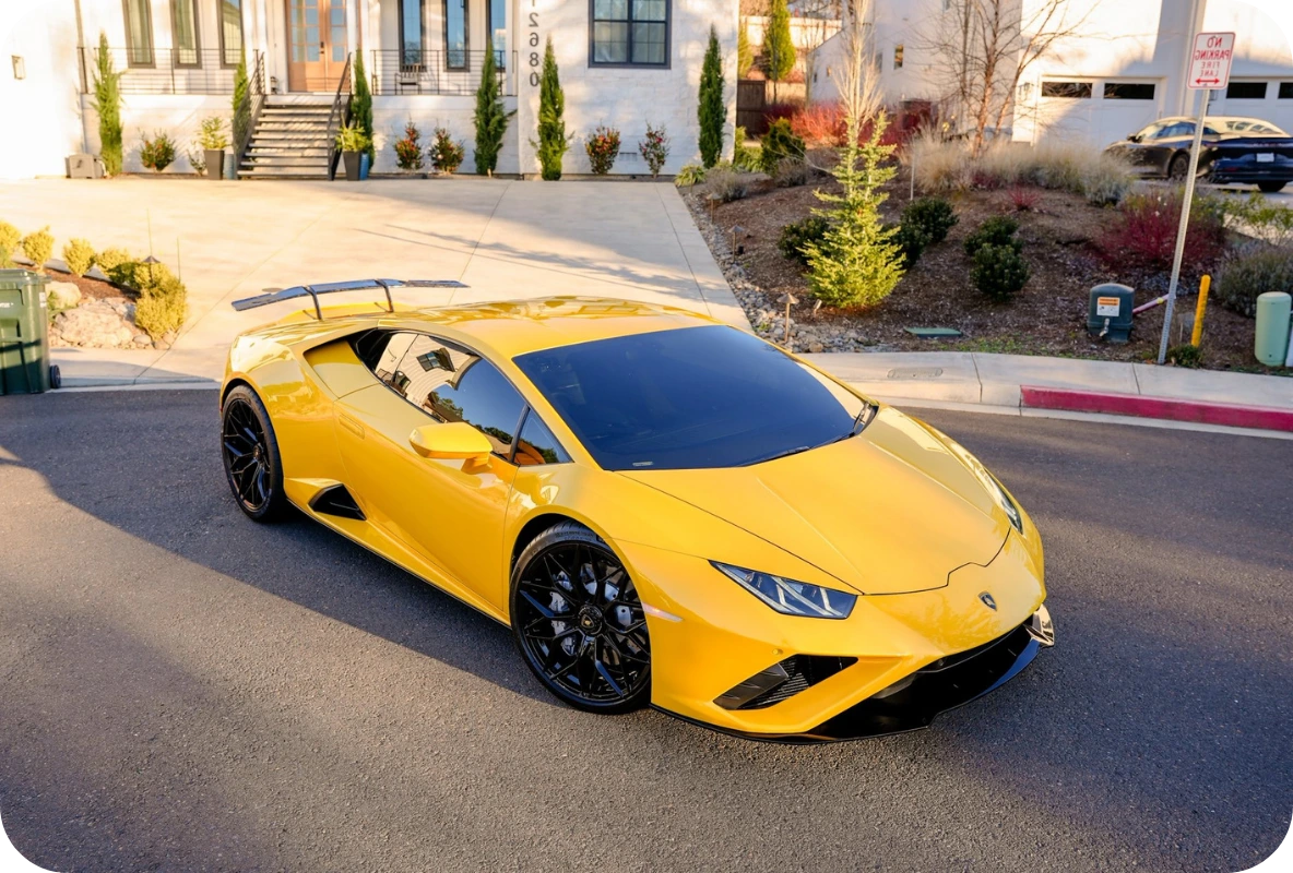 Yellow Lamborghini Huracán EVO parked on a residential street outside a modern home