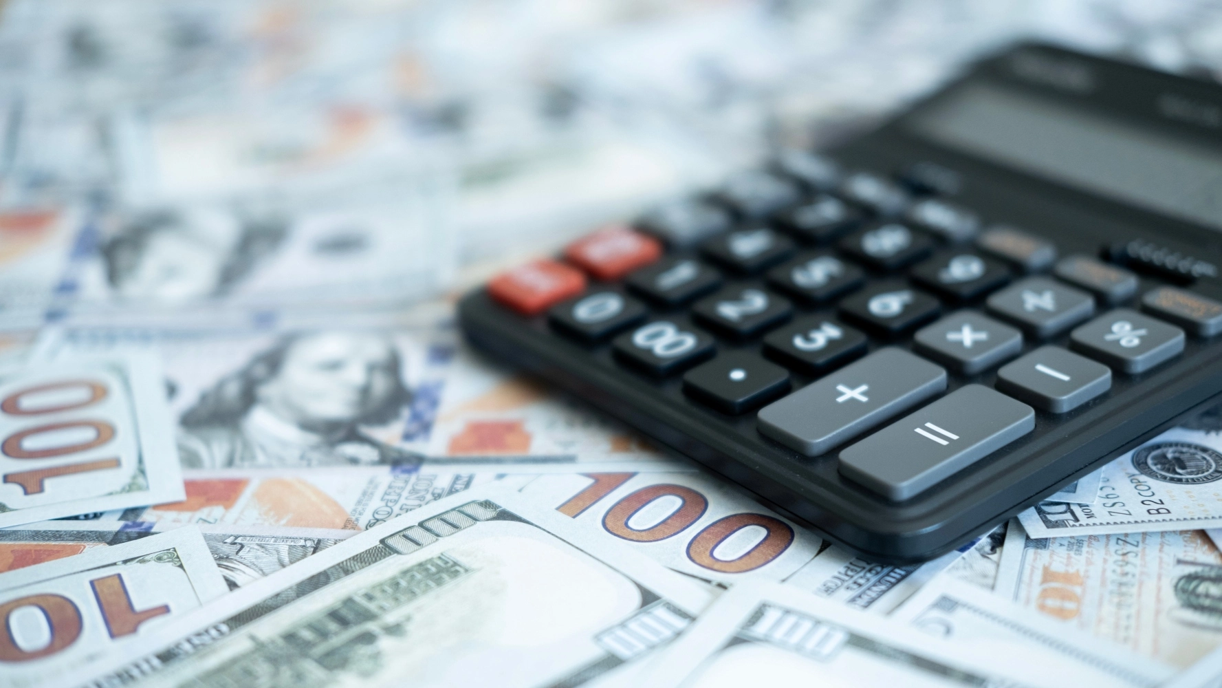 Calculator on U.S. dollar bills representing luxury watch loan-to-value ratio calculations for collateral loans