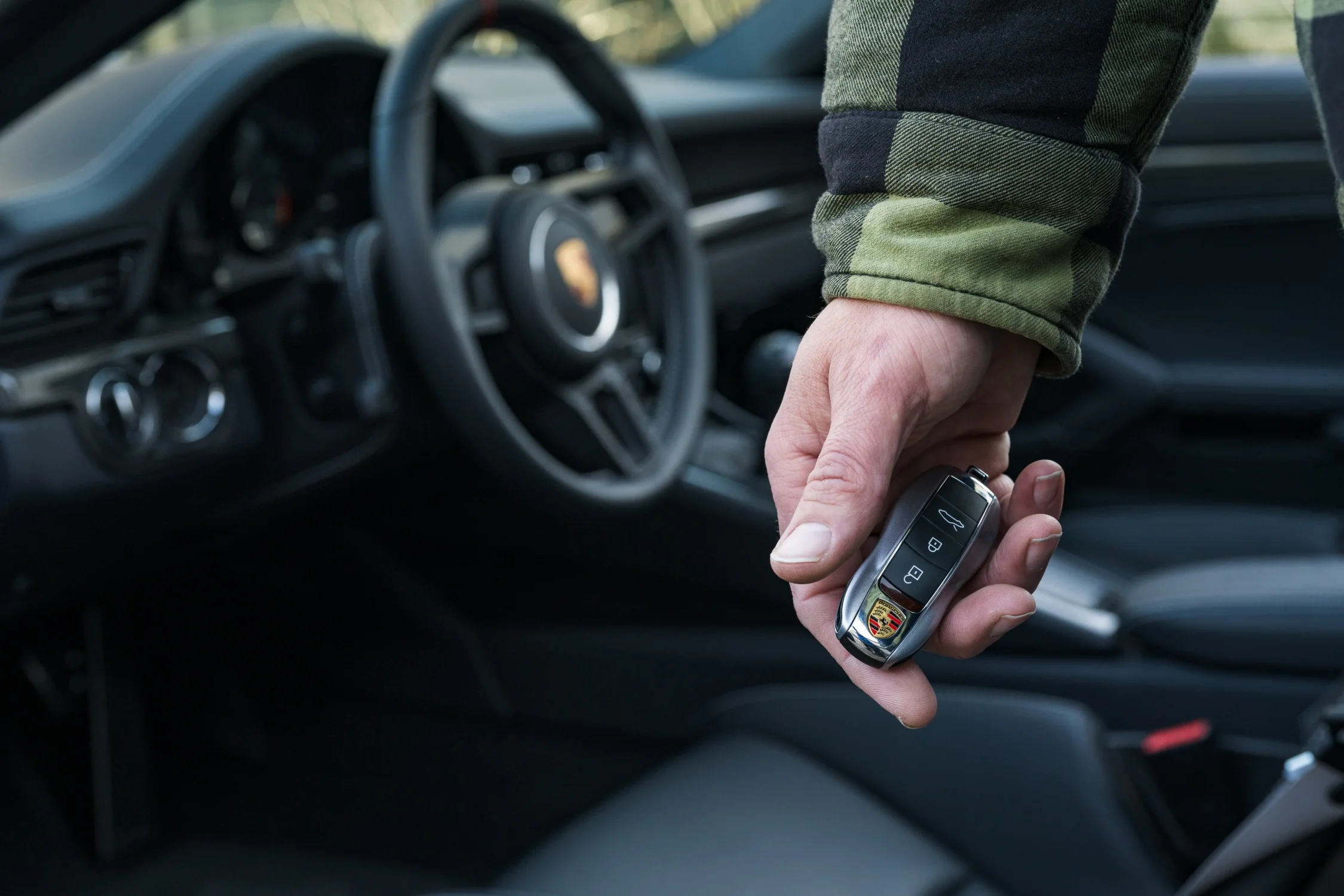 Person holding a Porsche key beside a luxury car representing exotic car ownership and collateral loans